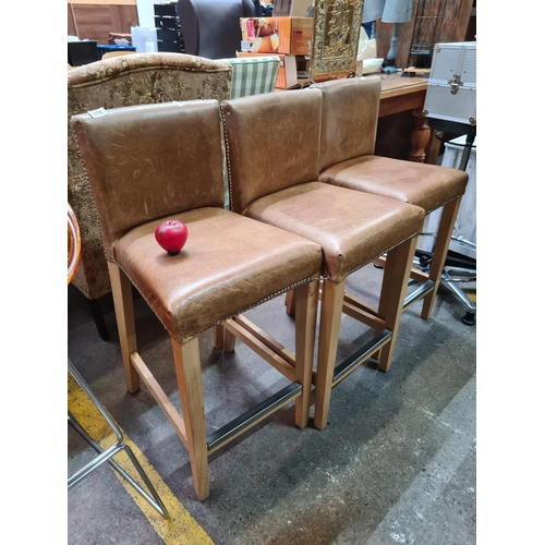 395 - A trio of stylish tan leather breakfast bar stools with a button back finish.