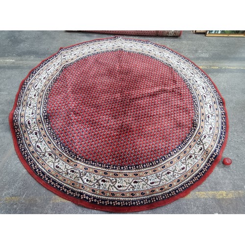 664 - Star Lot : A striking large circular Hand Knotted woollen rug boasting an intricate design in shades... 