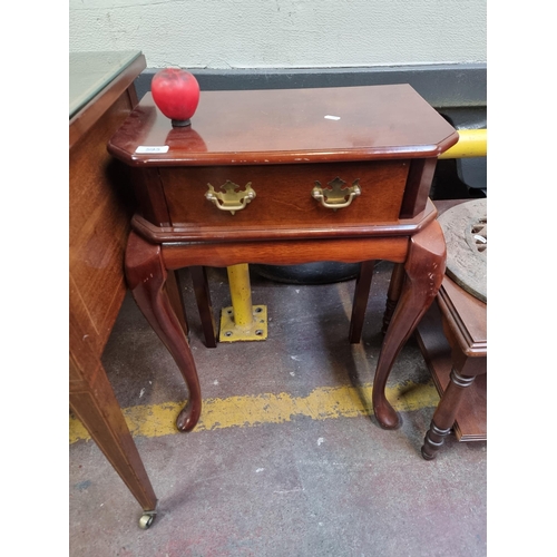 595 - An attractive side table with single drawer to front boasting two brass drop handles and held on cab... 