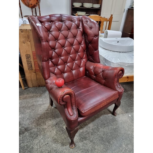 650 - Star lot : A striking Chesterfield style wingback armchair in an attractive red finish. Boasting but... 