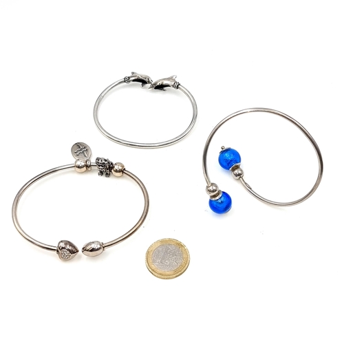 698 - Three sterling silver bangles featuring two gem set examples together with a dolphin dolphin feature... 