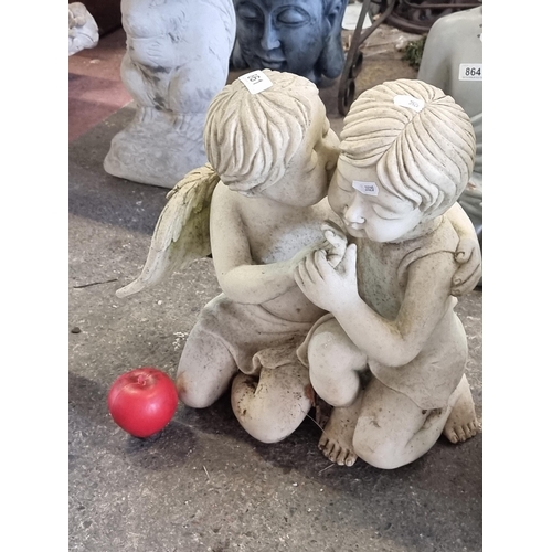 861 - A charming and heavy reconstituted stone garden sculpture of a pair of cherubs embracing.