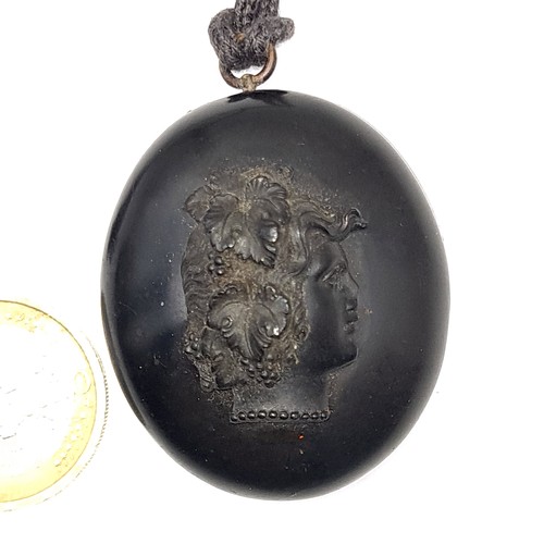 700 - A pretty and rare double sided prehistoric bog oak locket set with a fruit and vine motif with strin... 