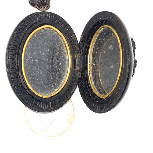 700 - A pretty and rare double sided prehistoric bog oak locket set with a fruit and vine motif with strin... 