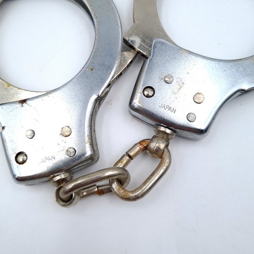 731 - A pair of handcuffs marked Japan with leather pouch. (Without key).