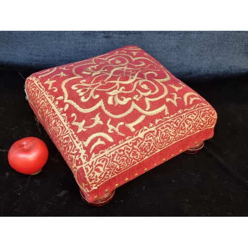 131 - A charming padded foot stool featuring red fabric and bun feet.