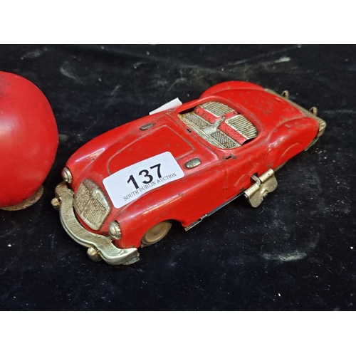 137 - A vintage Japanese made Sanshin tinplate wind-up car model in red. C. 1950s.