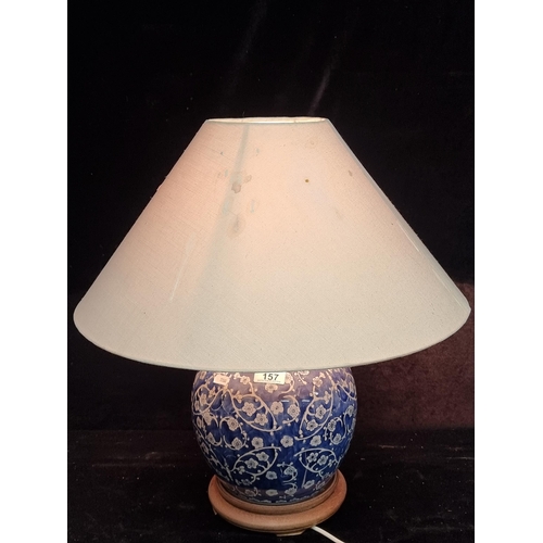 157 - An elegant large blue and white fine ceramic table lamp on turn wooden base. Features floral and but... 