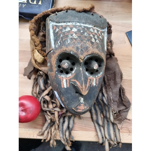 384 - An antique  hand carved African tribal mask featuring interesting hand painted detail and carvings.