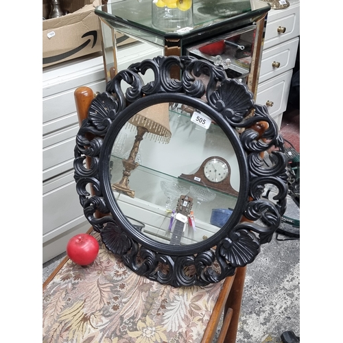 505 - A stylish circular wall mirror boasting pierced foliate detail.