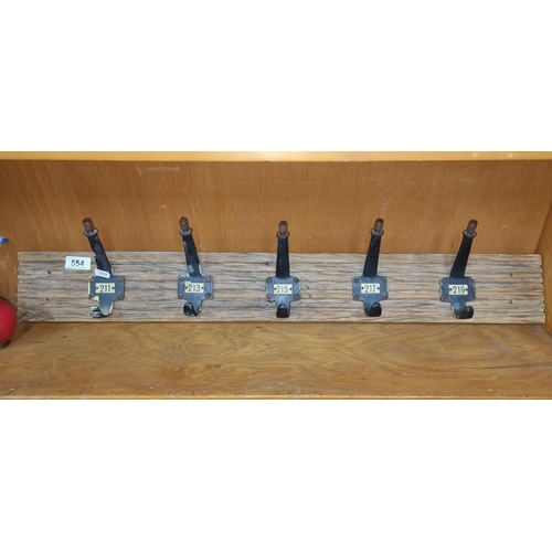 554 - A vintage industrial style wall coat hanger with five metal hooks featuring number plaques. Held on ... 