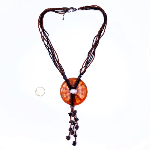 633 - A orange glass circular pendant with drop tassels features with multistrand bead necklace, length 50... 