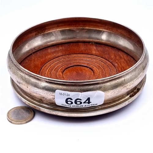 664 - A Georgian silverplated wine coaster with polished wood baise base, 13cm diameter, weight 140 grams.