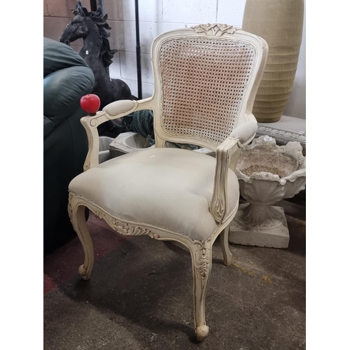 728 - A very chic occasion chair with canework to back, foliate carving to top and cushioned armrests, all... 