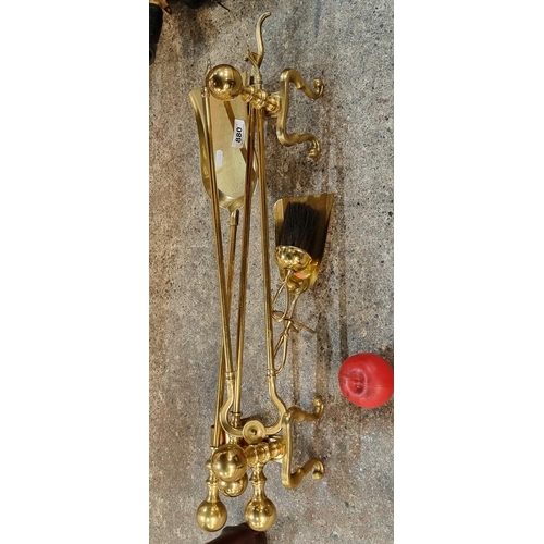 880 - Six brass fireplace companion items including fire dogs, tongs, a shovel, a brush and a poker. In lo... 