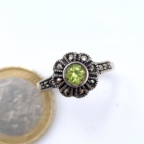 687 - An art deco peridot stone ring set in silver and marcasite detailing, ring size O, weight 3.53 grams... 