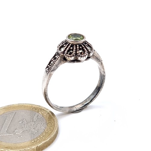 687 - An art deco peridot stone ring set in silver and marcasite detailing, ring size O, weight 3.53 grams... 