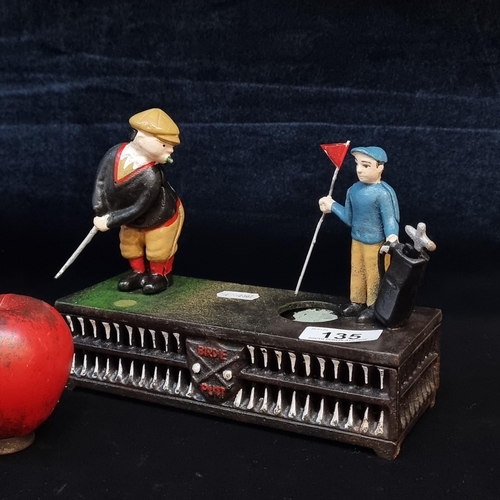 135 - A cast metal articulated money box in the form of golfers on a course. With working lever and coin s... 