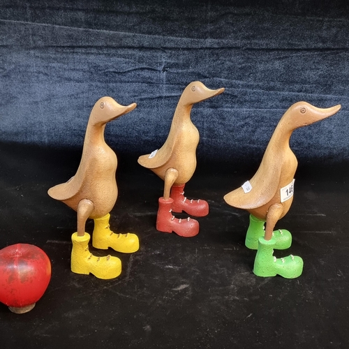 A set of 3 very heavy characterful cast metal duck figures wearing colourful boots.