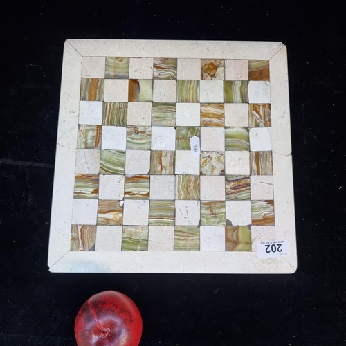 202 - An elegant stone chessboard featuring onyx detailing. Some slight losses.