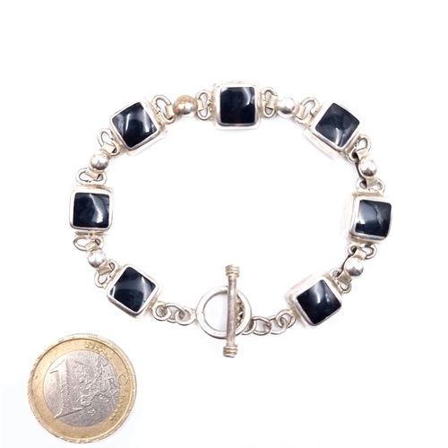 433 - A sterling silver seven stone black onyx bracelet with t bar clasp, weight of bracelet  21 grams.