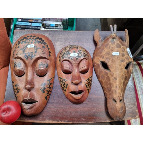 558 - Three hand carved wooden African tribal masks including one depicting a giraffe.