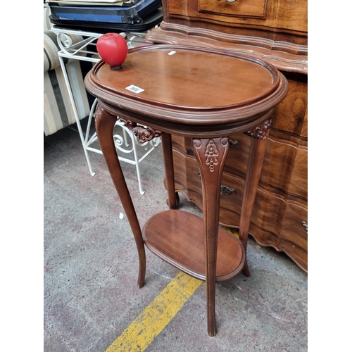 565 - An elegant side table featuring an oval top, shelf to base and intricate carved detailing.