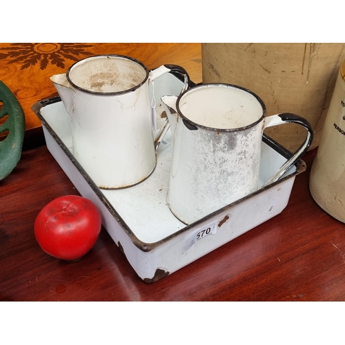 570 - Three vintage enamelled items including a baking tray and two jugs.