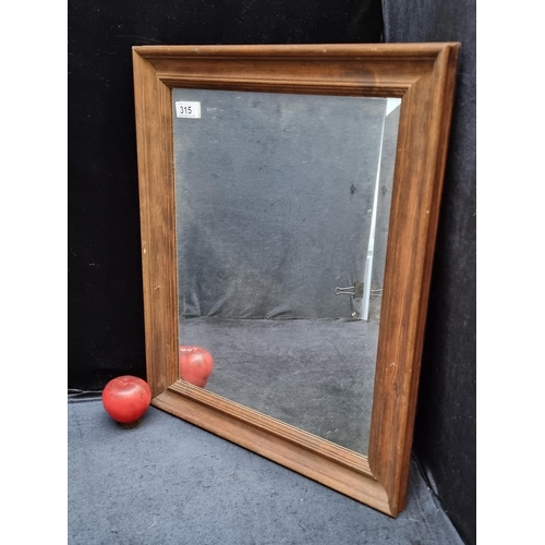 315 - A handsome vintage beveled wall mirror held in a stained wooden frame.