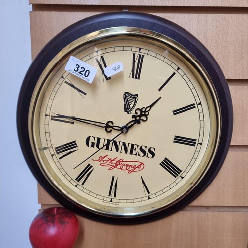 320 - An elegant Guinness advertising wall clock with glass front and brass surround.