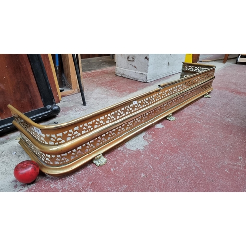 362 - A striking vintage brass fire fender with foliate pierced design and lion paw feet. SD to top bu we ... 