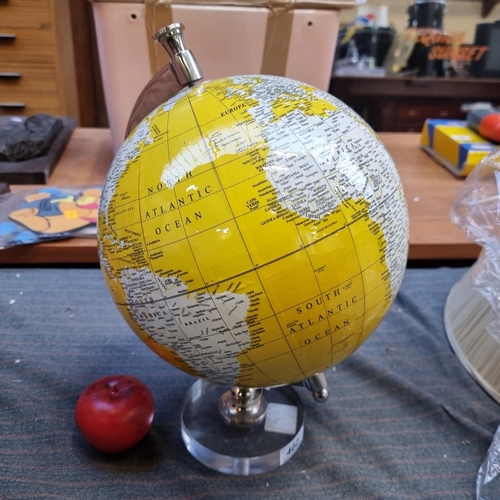 402 - An ornate desk top globe in an unusual yellow ground base and a chrome body and stand.