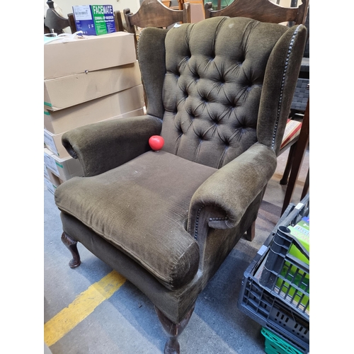 412 - A timeless Chesterfield style wingback armchair with buttonback detailing and brown plush upholstery... 