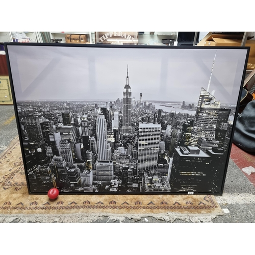 818 - A very large photographic print on canvas of the fabulous New York skyline. Housed in a black wooden... 