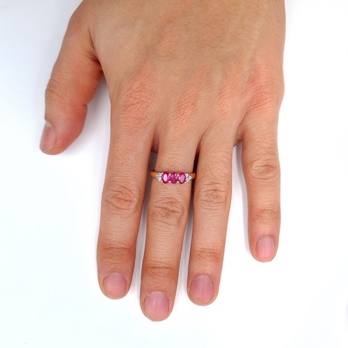 490 - Star Lot : A pretty three stone ruby ring with diamond shoulders set in 10K gold, ring size Q, weigh... 