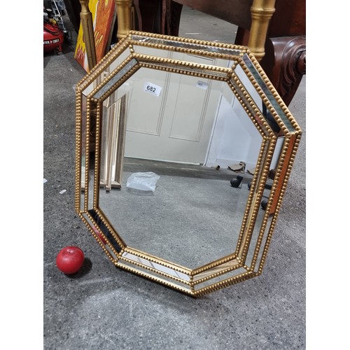 682 - An ornate octagonal beveled wall mirror featuring a gold toned beaded trim, with mirrored panels to ... 