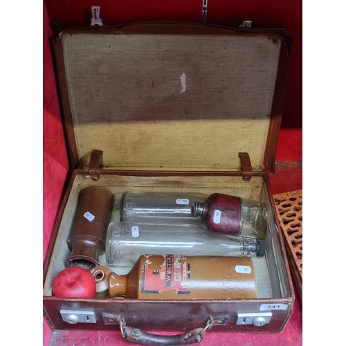 341 - A vintage suitcase containing five bottles including stoneware and glass examples with two made in B... 