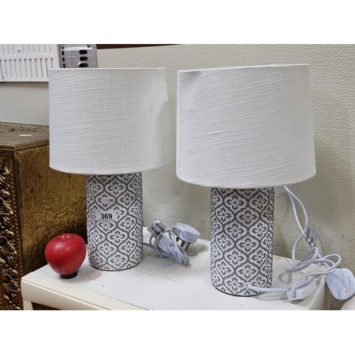 369 - Two heavy stylish table lamps with ceramic bases in a quatrefoil pattern.
Topped with white muslin s... 