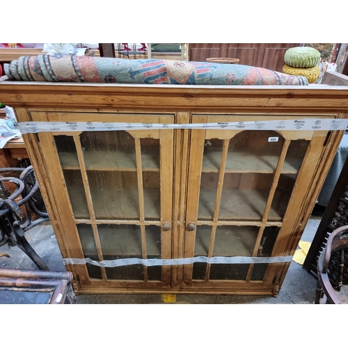 408 - Star Lot : An antique Pine display cabinet with two glass doors revealing three shelves, glass in go... 