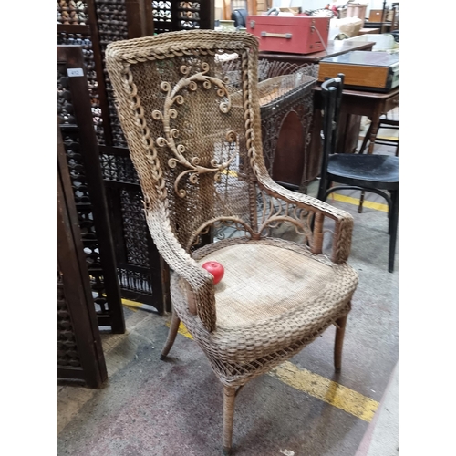 411 - A spectacular antique wicker occasional chair with an ornate detailing to backrest in the form of th... 