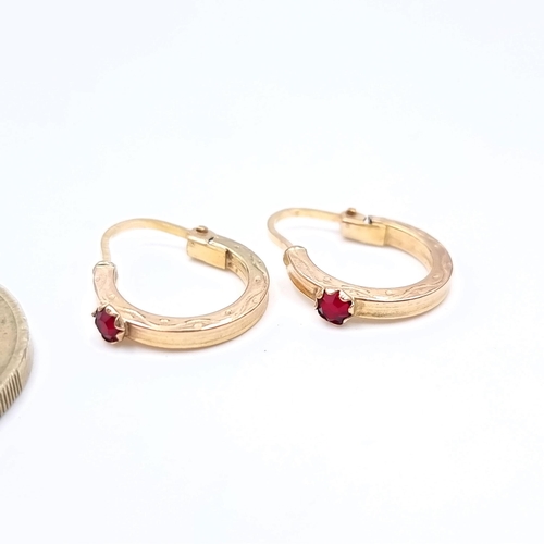 724 - A pair of 9K gold hooped earrings set with garnets suitable for pierced ears.