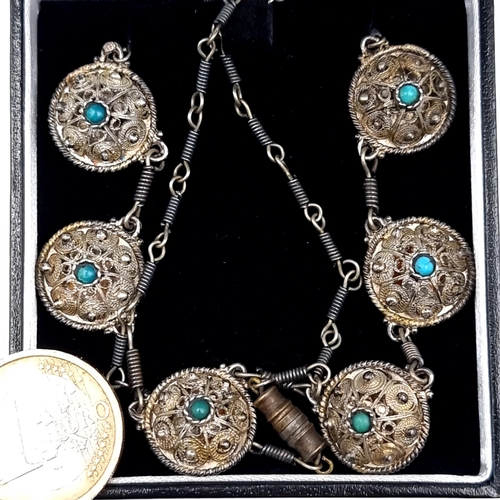 772 - A vintage Middle Eastern silver necklace set with six shield design panels, with central turquoise s... 