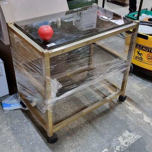 870 - A lovely vintage drinks trolley with three tempered glass shelves in a smokey brown shade. Held in a... 