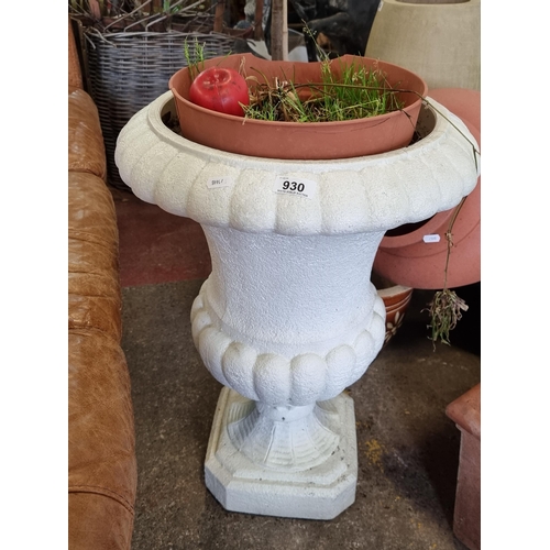 930 - A neo classical style garden planter in the form of a Grecian urn, holding a plastic planter. In a f... 