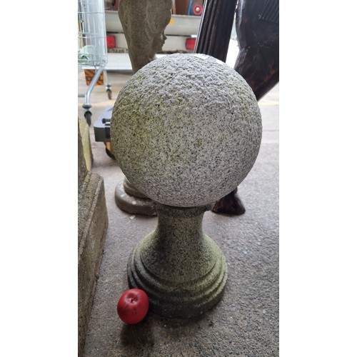 947 - A heavy granite garden feature, comprising of a sphere held on a pedestal with fittings to make it i... 