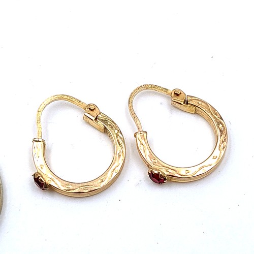 724 - A pair of 9K gold hooped earrings set with garnets suitable for pierced ears.