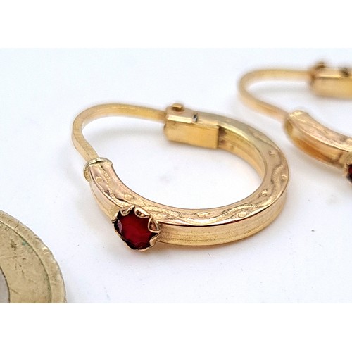 724 - A pair of 9K gold hooped earrings set with garnets suitable for pierced ears.