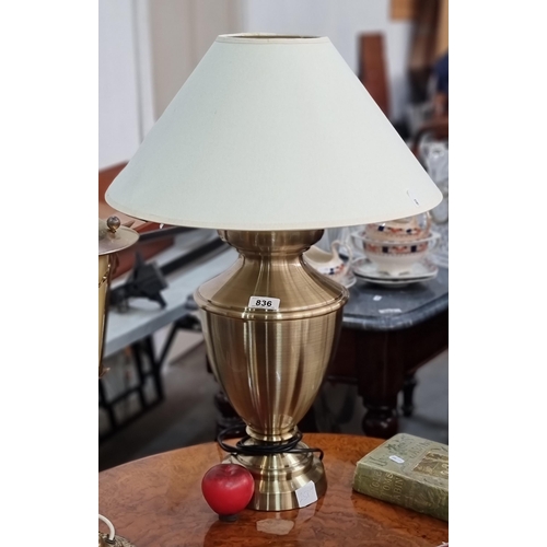 836 - A large striking brass table lamp in the form of an urn with white shade.