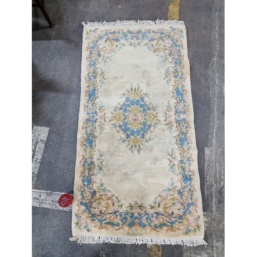 846 - A good Chinese wool carpet in shades of cream pink and blue. 135x72cm