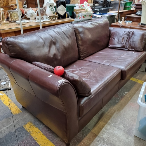 677 - A handsome two seater sofa upholstered in a super soft chocolate brown leather fabric. With two matc... 